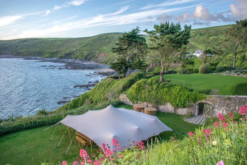 A large lawn with a stretch marquee on the ege of a cliff