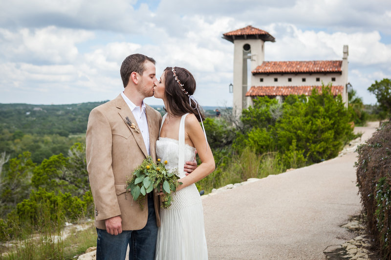 bride and groom kiss in front of wedding chapel