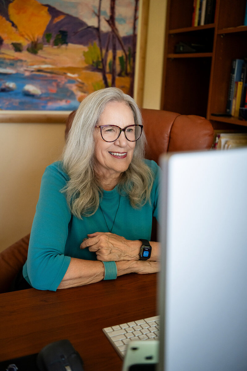 Audrie Meyer smiling while coaching a client online, providing 1:1 spiritual guidance and support.