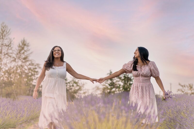 Mom and senior grad daughter walking in lavender field holding hands