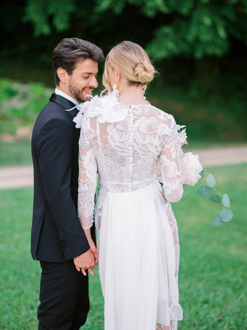 groom looking at bride in beautiful floral appliqué wedding gown