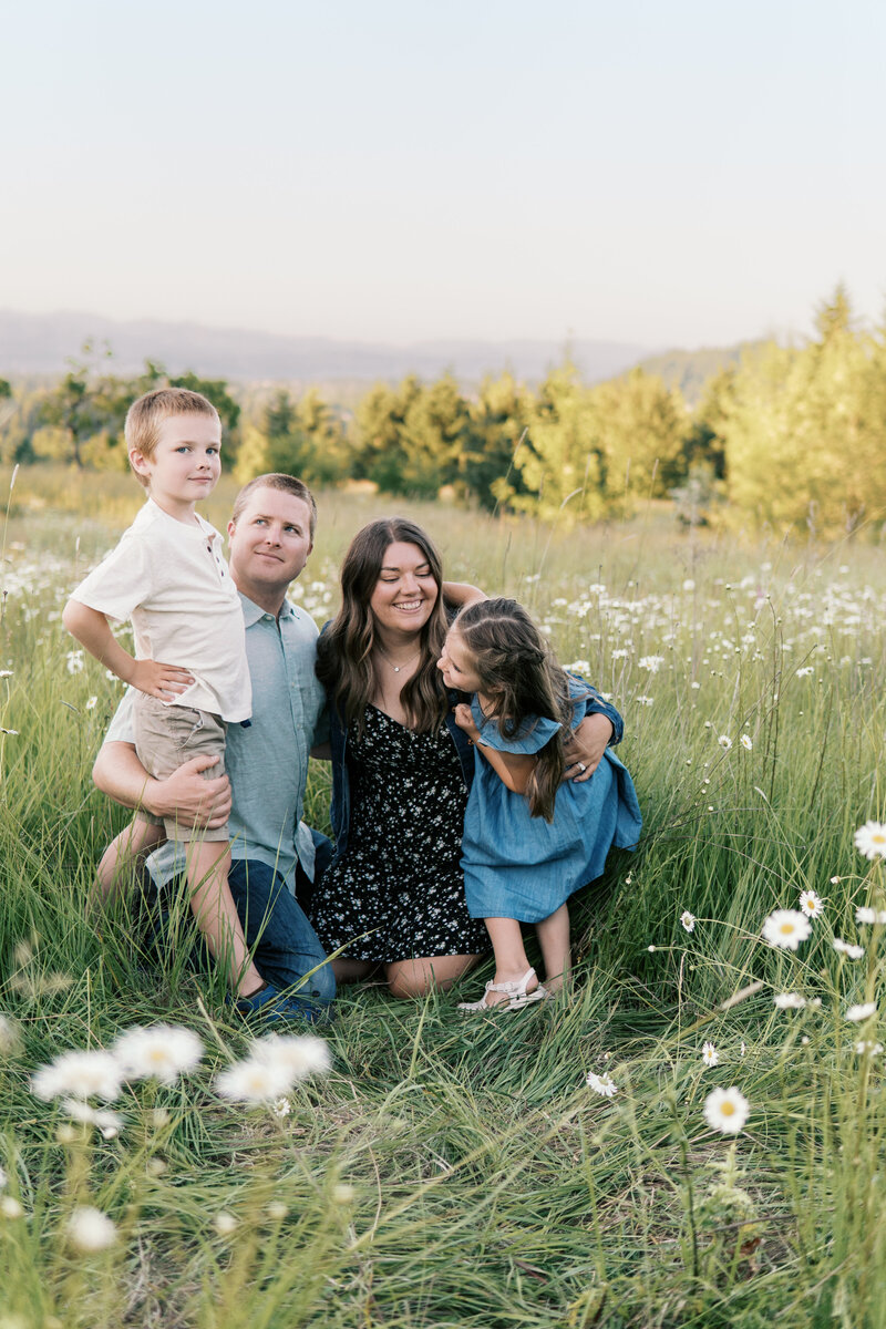 Portland family photography session with parents and children sitting together in a wildflower field during golden hour.