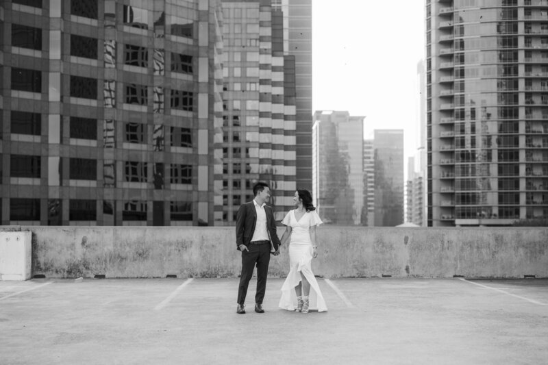 black and white image of a couple with tall buildings as their background