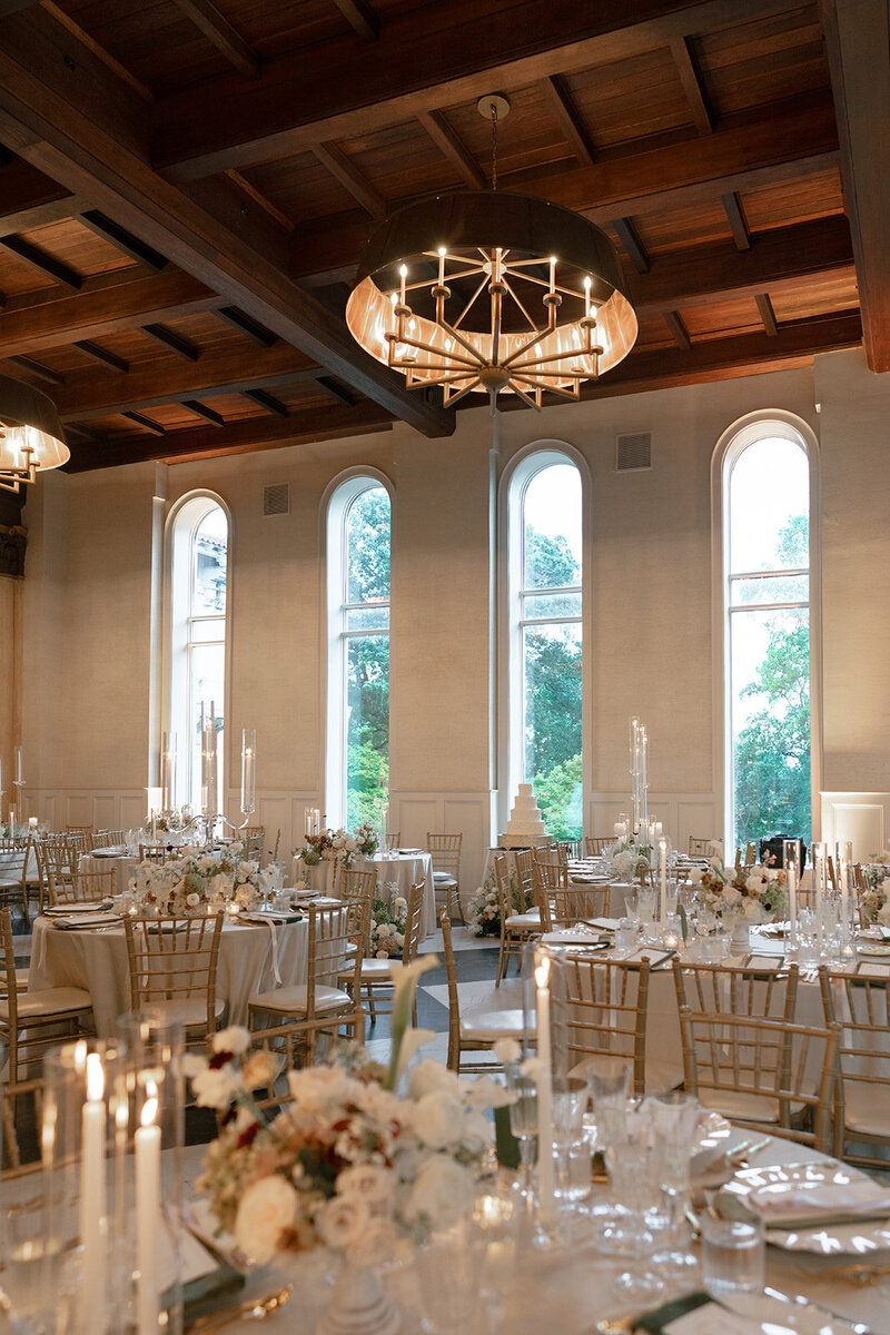 The Elkins Estate reception room with arched windows, a beamed ceiling and candlelit tables