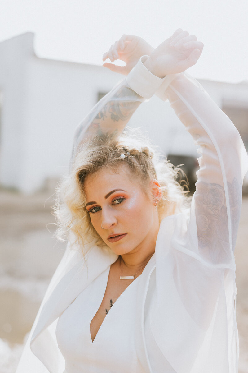 Wedding photo session of tattooed bride with arms crossed above head