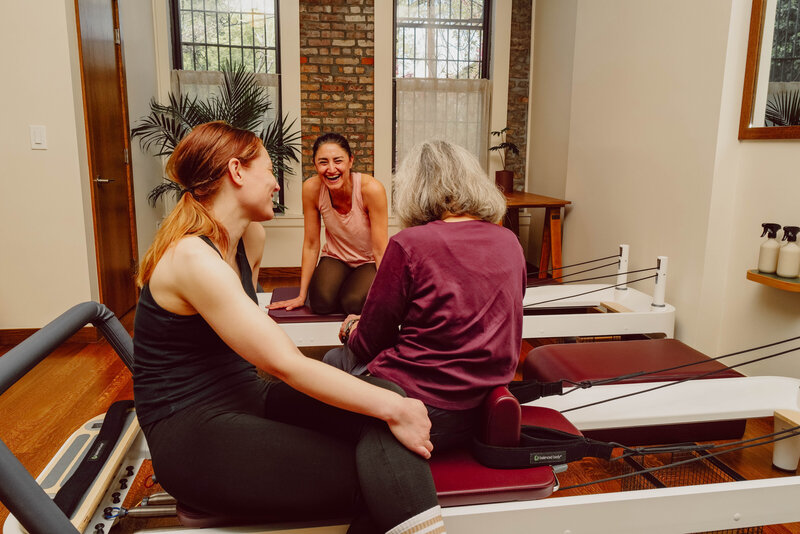 Community members chatting, while sitting on their reformers before class