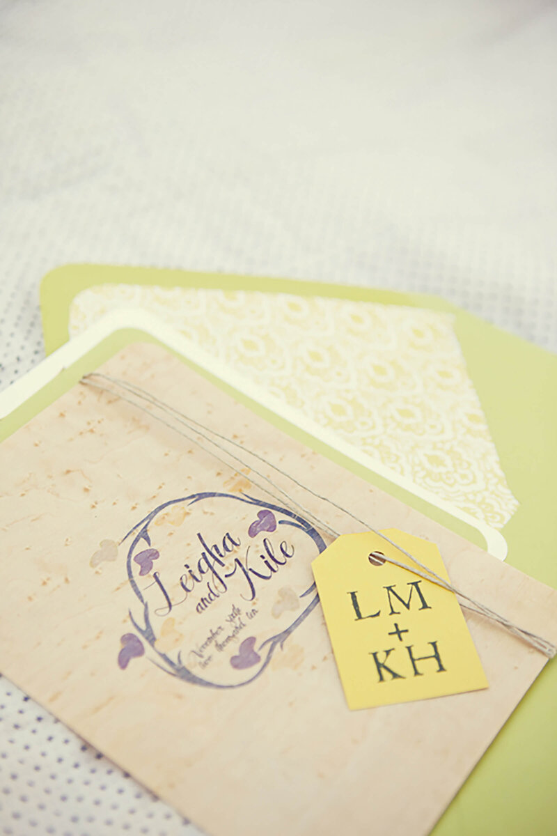 Whimsical cabin wedding invitation on birdseye maple wood veneer, wrapped in hemp twine with a tag featuring the couple's initials.