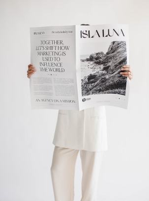 A women in a white blazer set posing with a newspaper 
