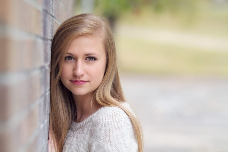 Senior portrait of a girl leaning against a wall