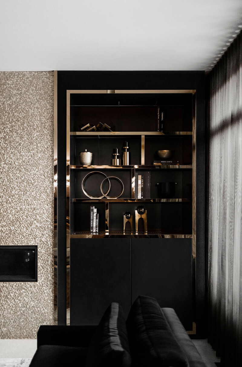 A built in shelf with walnut, brass and black and gold metallic accent tile.
