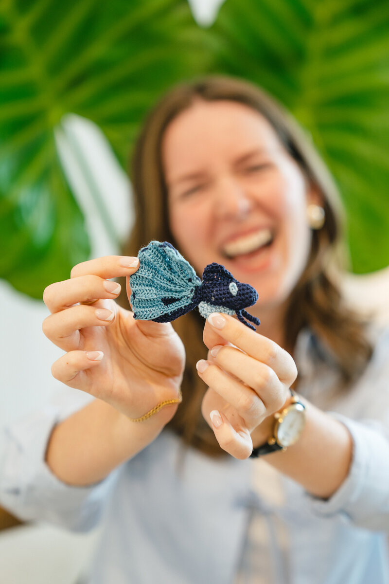 photo of matilyn smiling and holding a crochet betta fish created by her sister