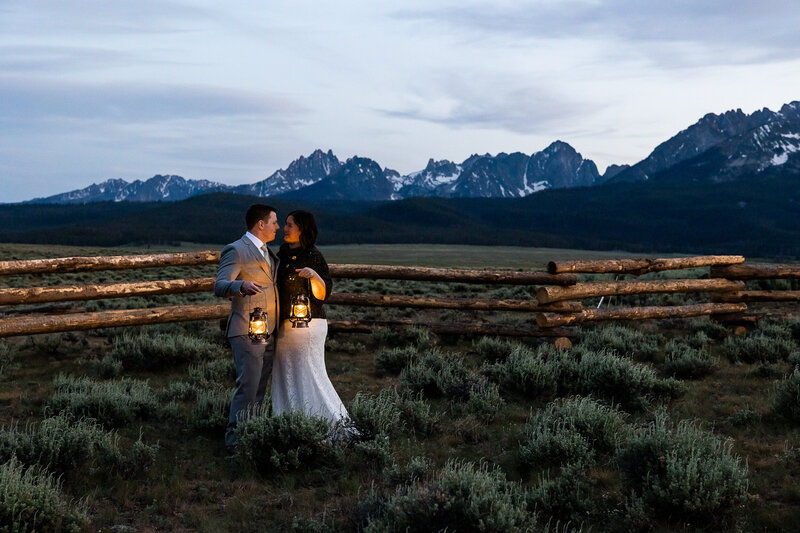 Bride and gromm facing each other holding lanterns during blue hour in the Sawtooth Mountains