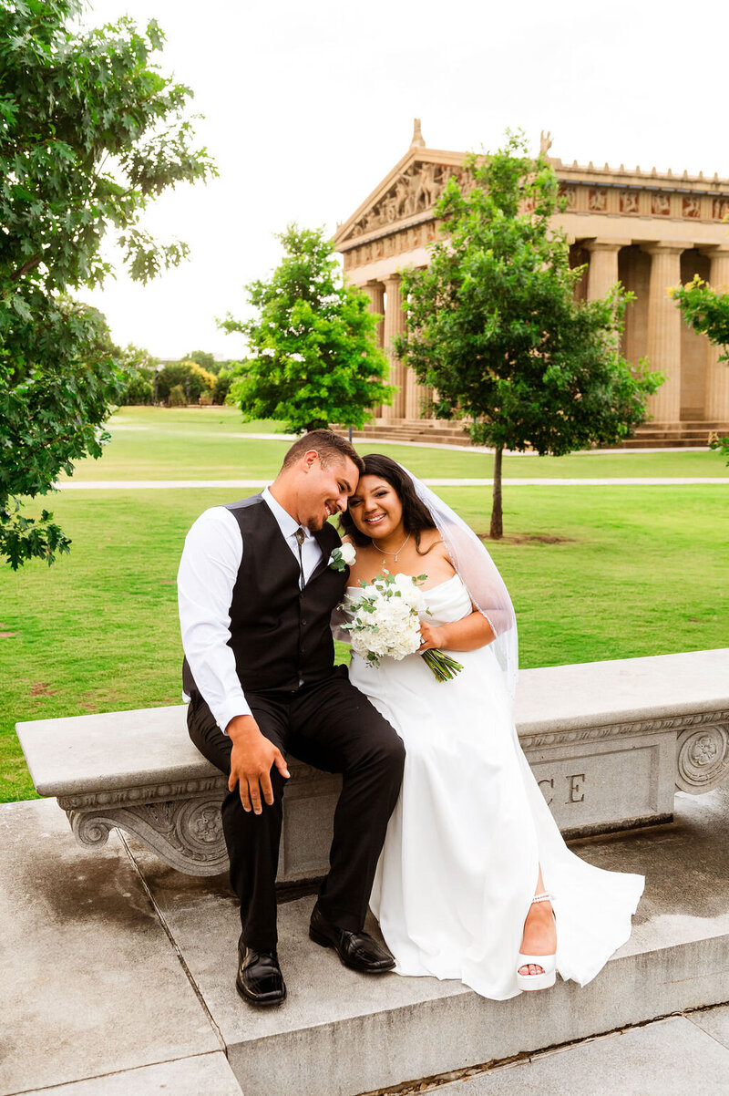Candid photo of bride and groom laughing during their elopement photos in Centennial Park with the Parthenon in the background.