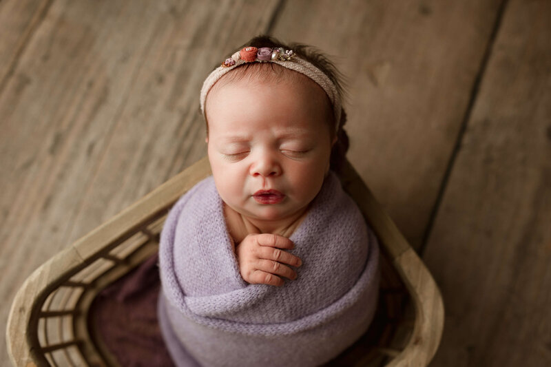 newborn-baby-girl-in-purple-wrapped-swaddle