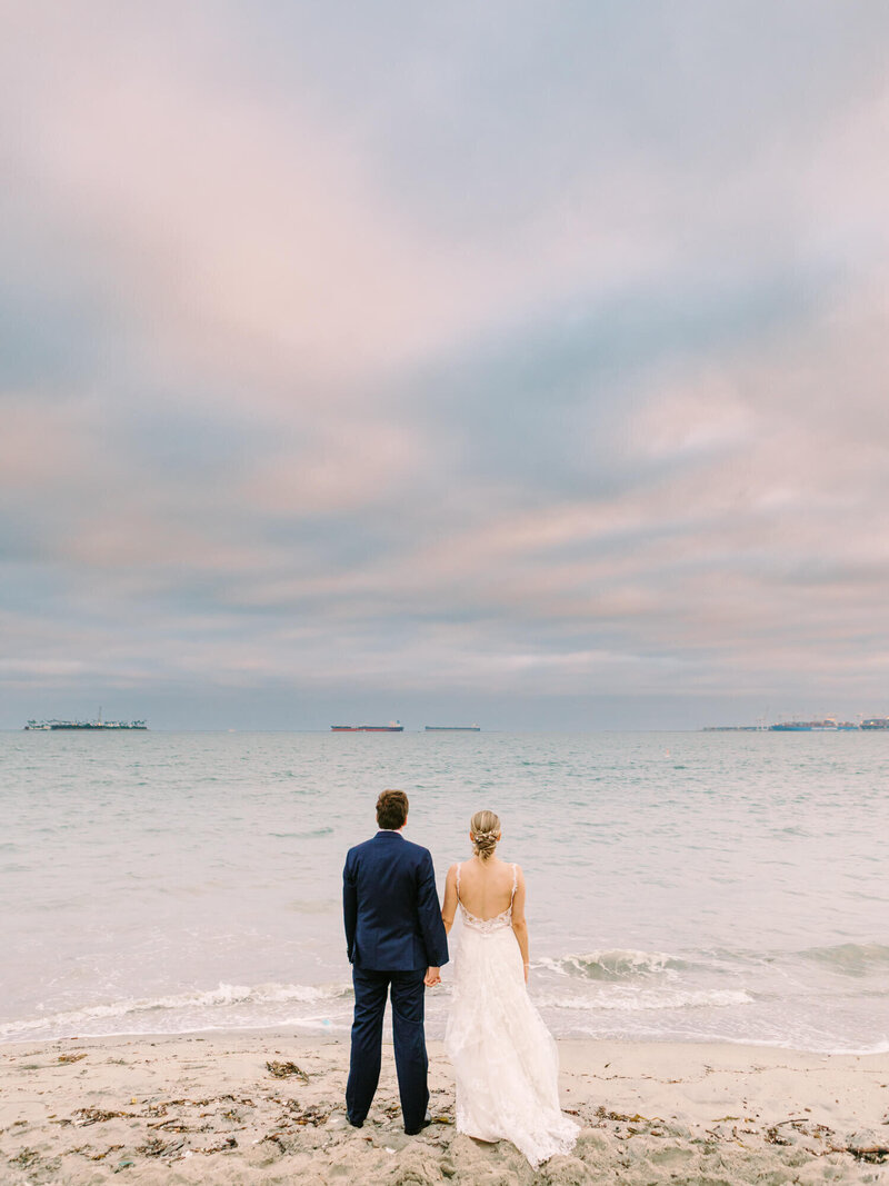 cloudy pink and blue photography of bride and groom overlooking the pacific ocean