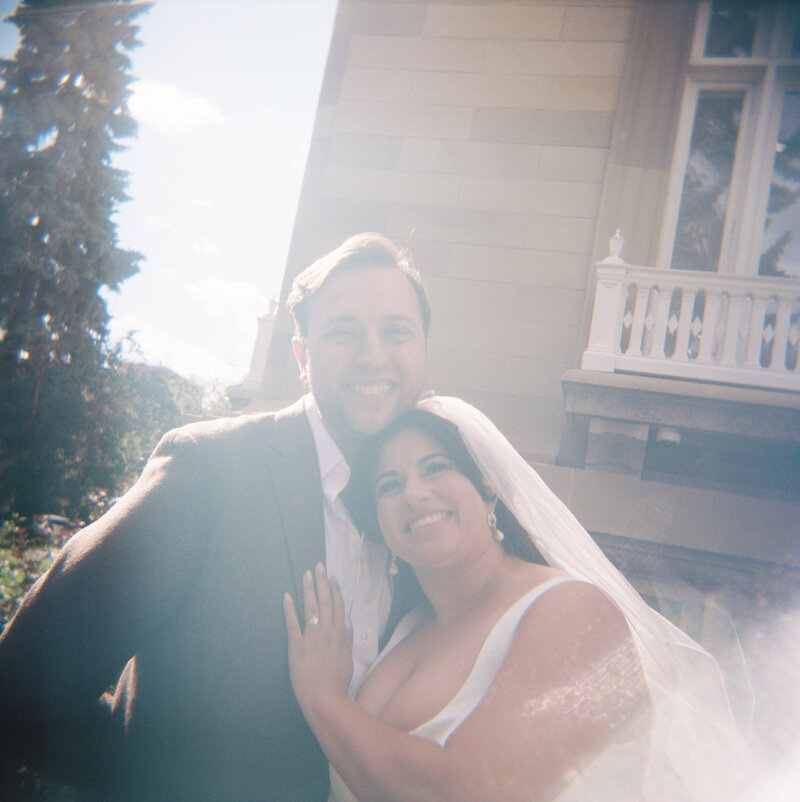 bride leaning on groom and smiling at the camera