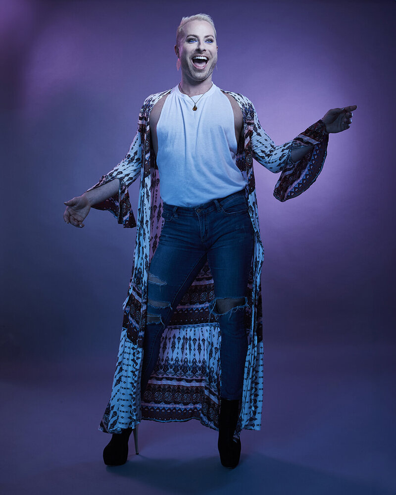 Stylish portrait of Dain August gesturing confidently in a sparkling blue ensemble, photographed by Ylva Erevall.