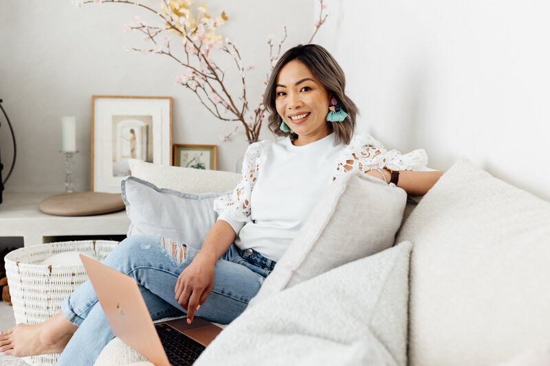 A lifestyle branding photoshoot of business owner working on her laptop in a bright, stylish home setting, showcasing her approachable and professional vibe.