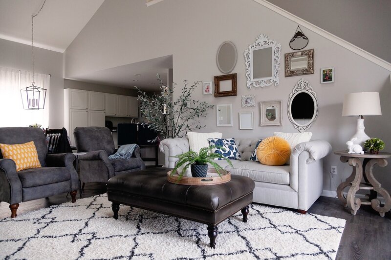 Modern living room with a leather ottoman, suede chairs and a bright couch.
