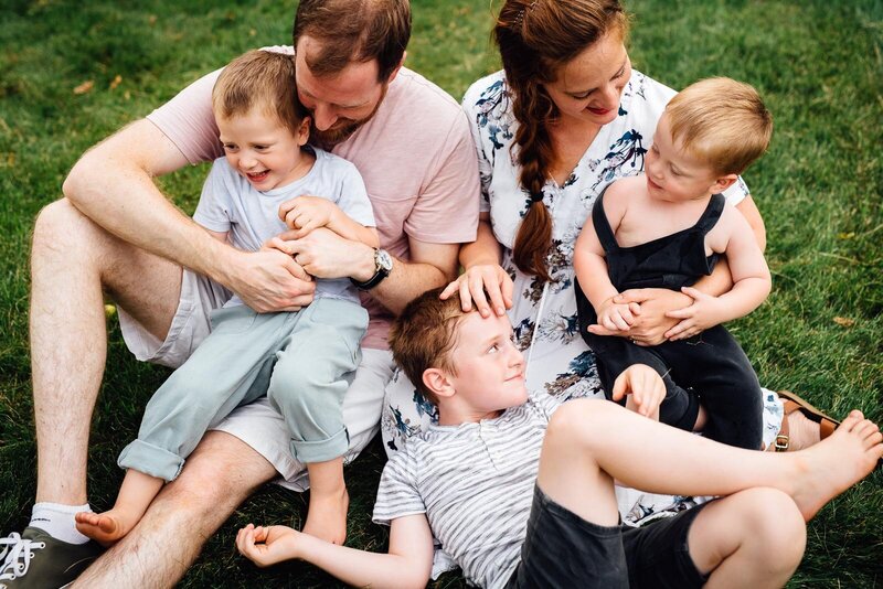 family embracing with laughter sitting on grass