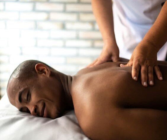 Therapist performing focused massage on a man's back, supporting post-surgery recovery and muscle relief.