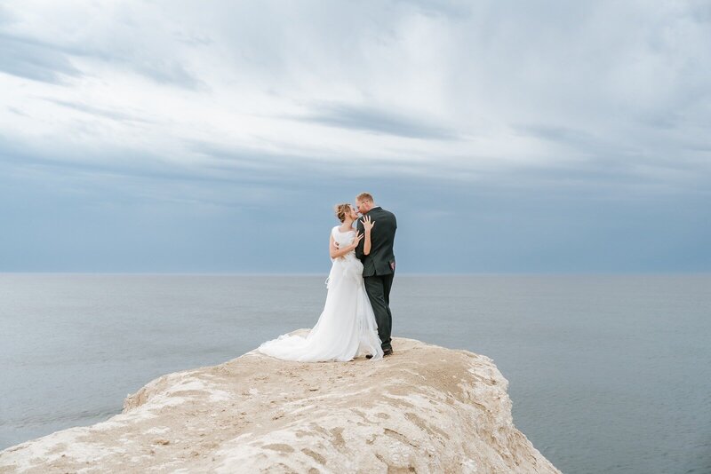 A bride and groom standing on Maslin cliffs in South Australia overlooking the ocean