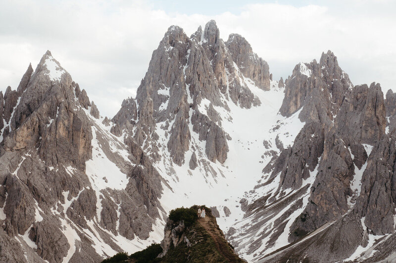 Dolomites Elopement at Cadini Di Misurina, couple stands on a viewpoint with the huge mountains behind them