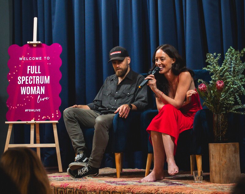 Relationship coach Jacob O'Neill sitting on a velvet couch holding his wife's legs
