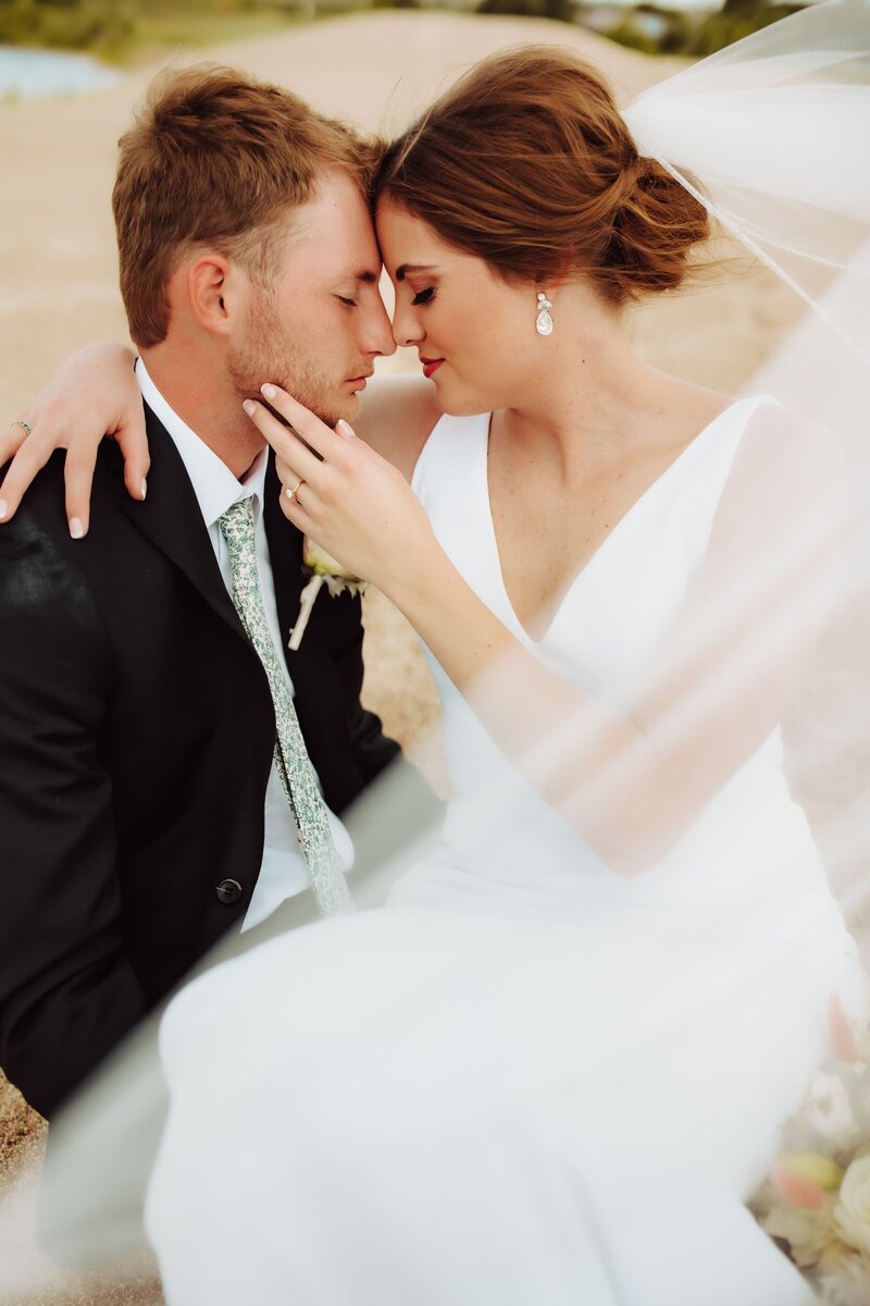 A bride and groom touching noses in an intimate moment captured by Infinite Productions