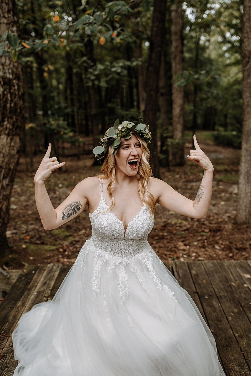 A woman dressed in a wedding dress putting up "rocker horns"