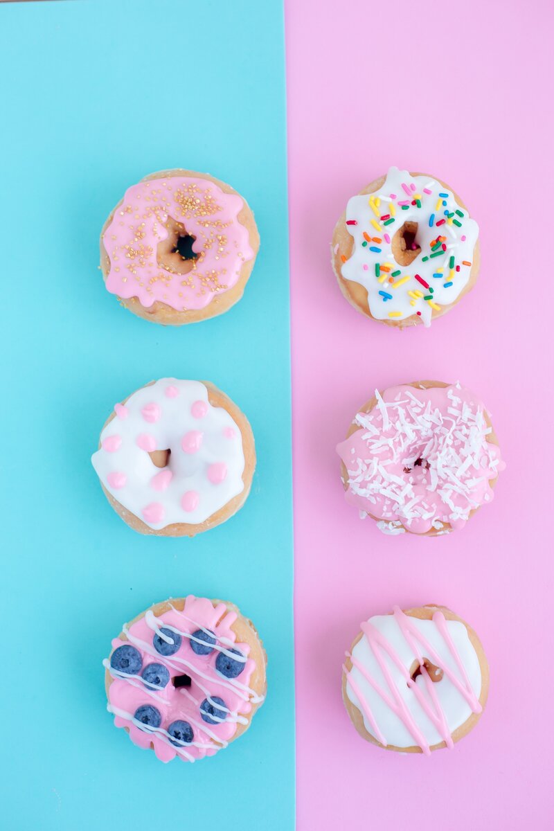 an assortment of frosted donuts shot from above on a half blue, half pink background socialfizz