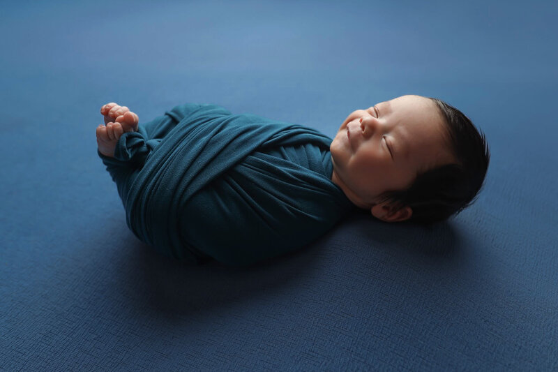 Newborn dressed as Satna Clause asleep in his chair with a cookie in his lap.