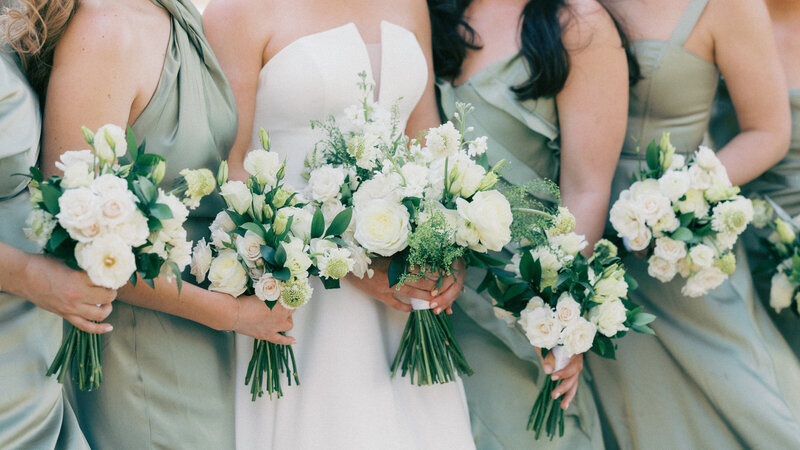 Bridal party standing outside with groom opening bottle of champagne