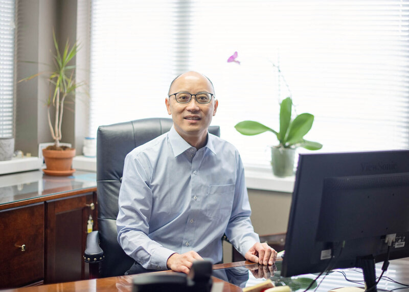 Raymond J. Kao, DMD smiling at his desk at Kao Dental office