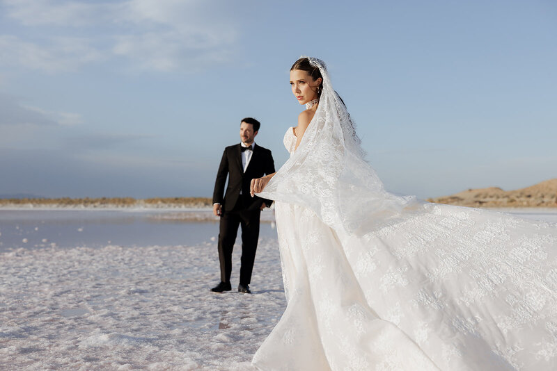 bride and groom pose on sandy beach