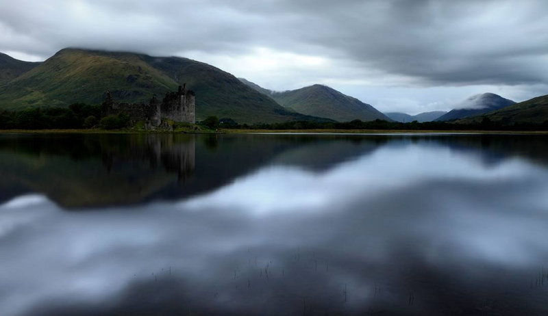Kilchurn Castle reflected in the still waters of Loch Awe beneath brooding Highland skies — a cinematic reminder of the wild beauty and emotional depth woven into Kat Mackenzie’s Work in Progress Literary Tour.