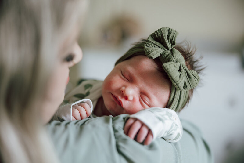A close up image of an infant at home on her mom's shoulder.