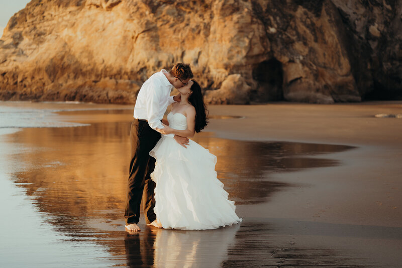 a bride kissing her groom on the beach