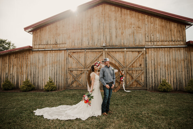 Bride and groom posing in front of a barn
