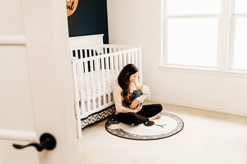 mother cuddles her baby boy in his nursery.