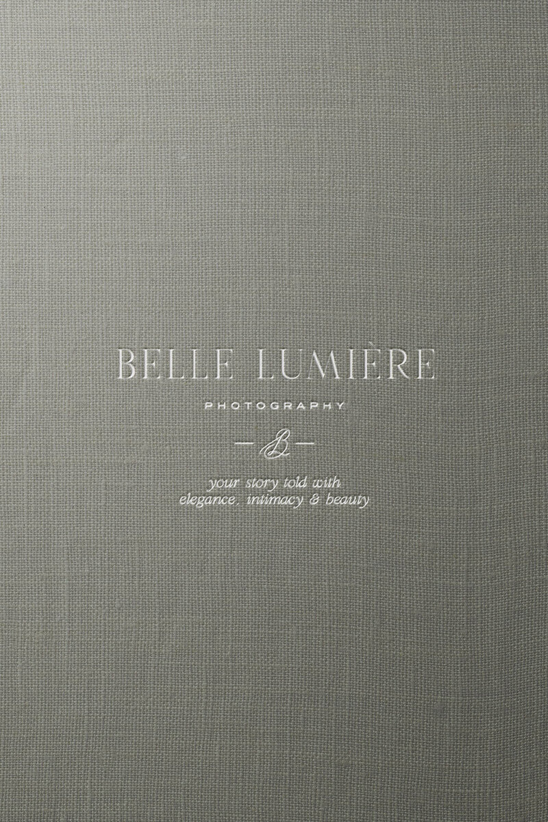 Debossed logo design for Belle Lumière on soft sage green linen background — branding by Sarah Shuttle