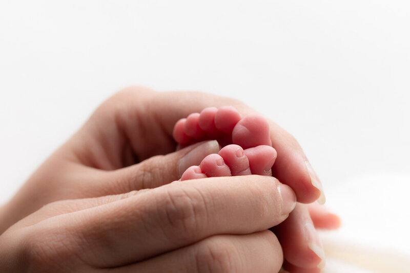 parent-holding-newborn-baby-feet-detail