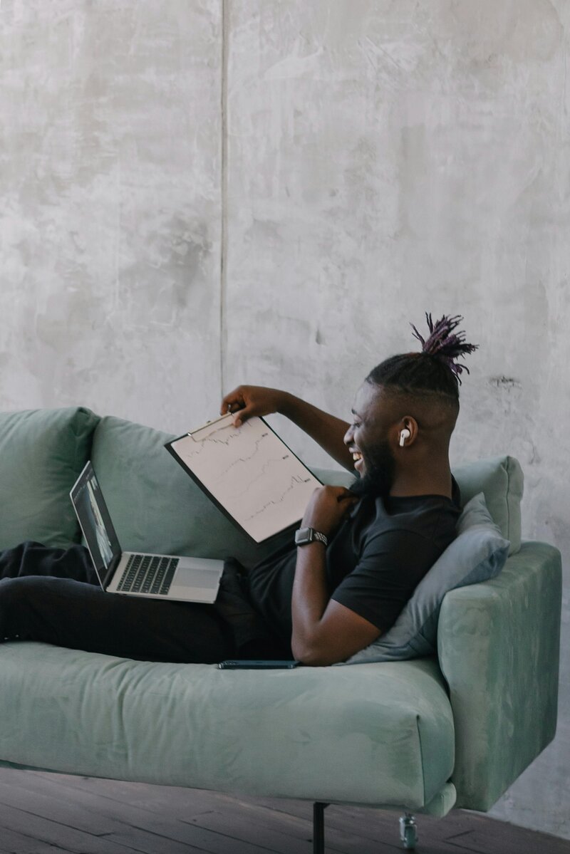 man laying on couch with computer
