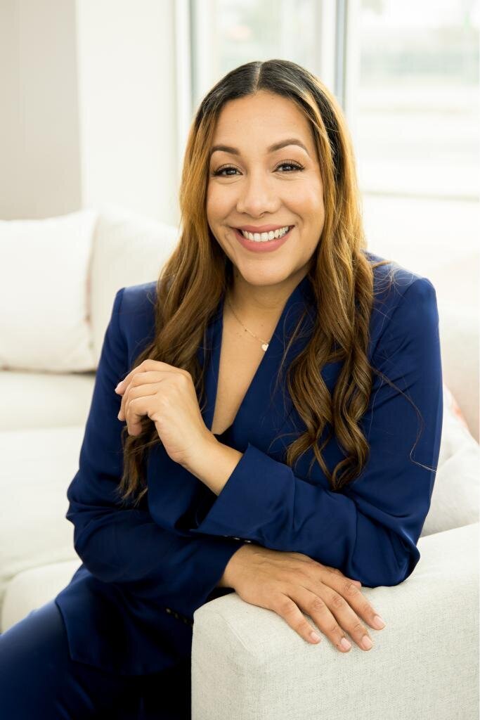 Maria Rivera Founder of Lapaz Group leaning against the arm of a couch smiling during her personal brand photo session.