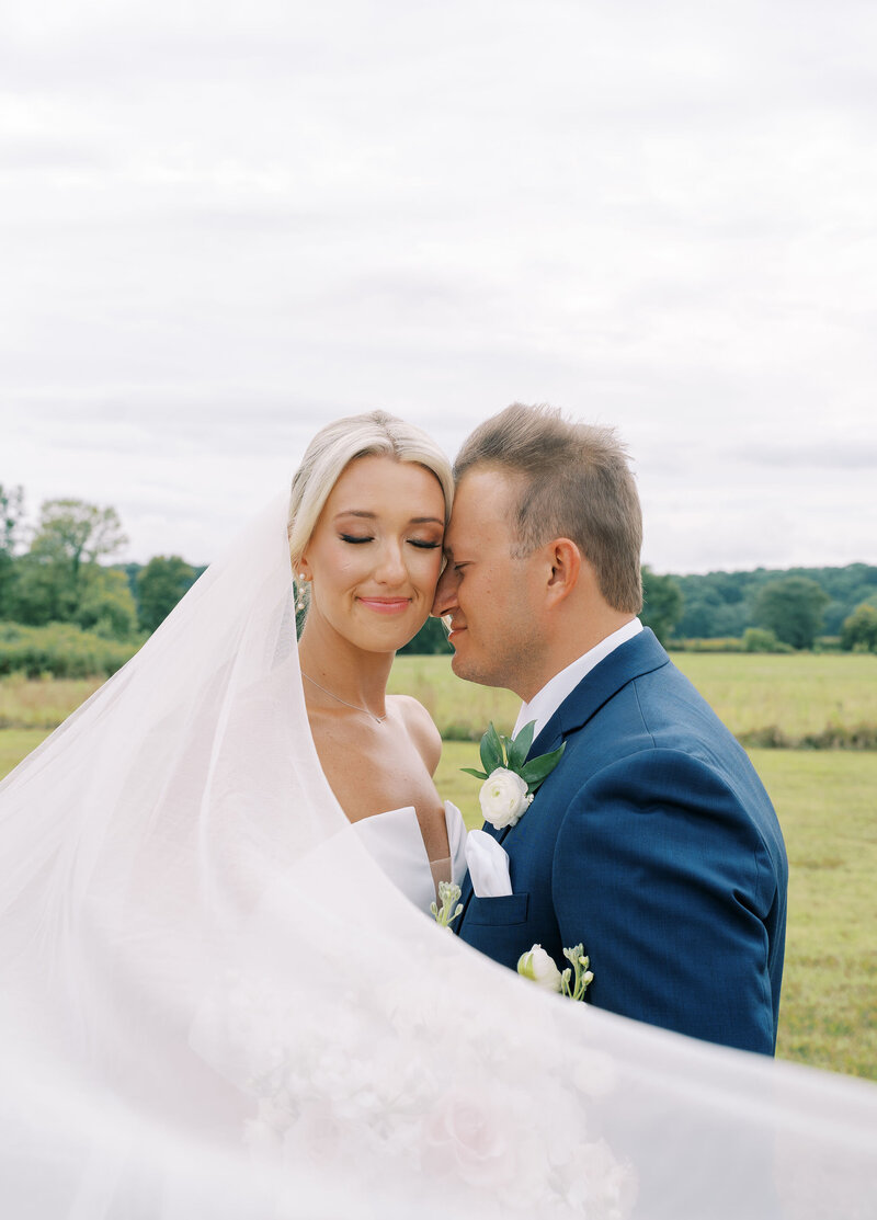 bride and groom embracing while wrapped in veil