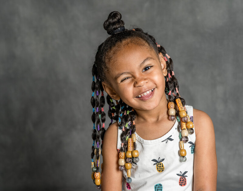 A child winks while smiling at the camera.
