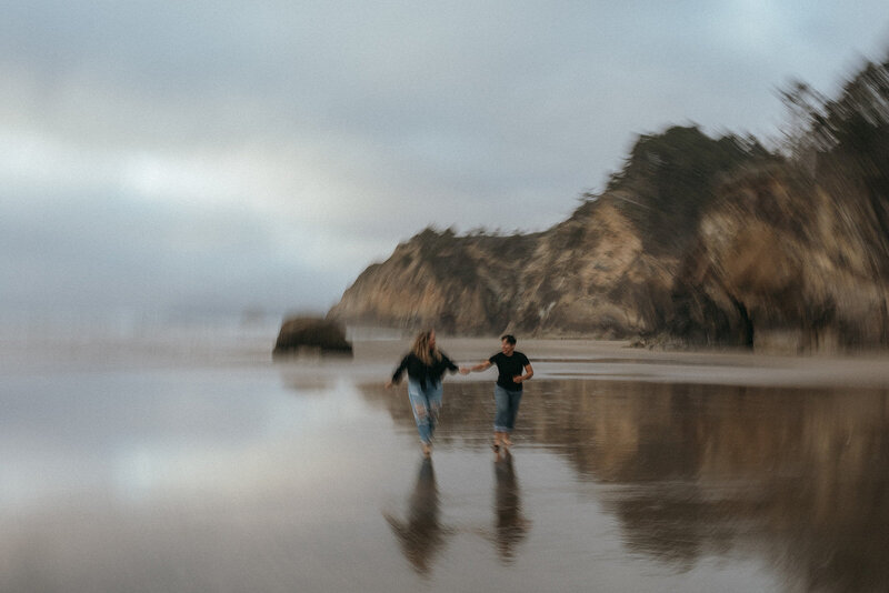 couple holding hands running on beach