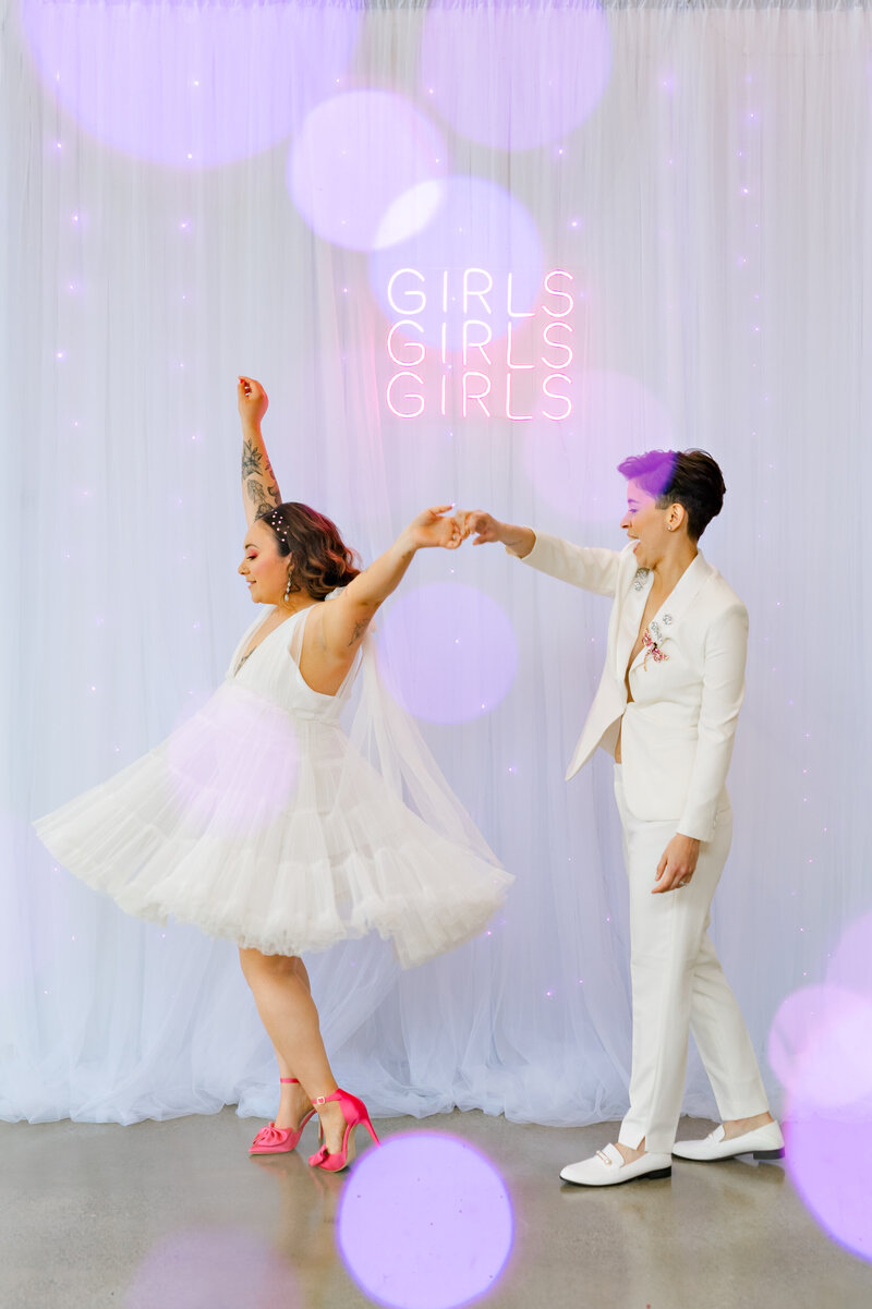 Bride twirling in her wedding dress while holding bride's hand