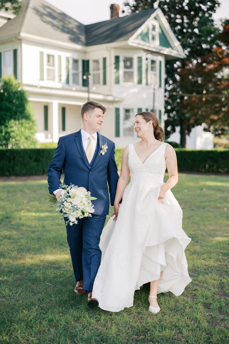 Bride and groom walking together in grass as virginia wedding photographer document them together