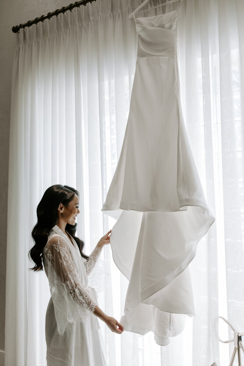 A bride admires her dress while smiling at The Stirling Club